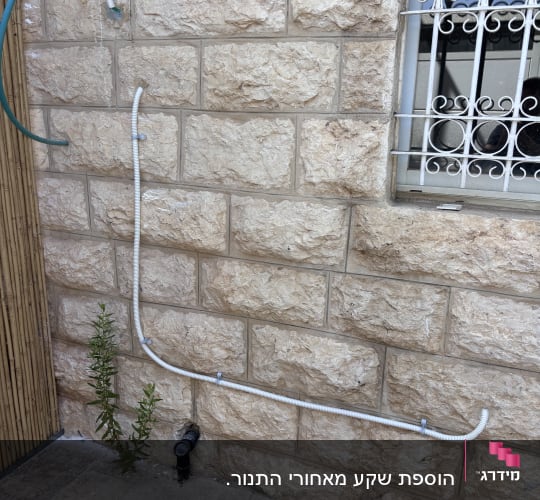 קיר אבן עם צינורות חשמל וחלון עם סורגים